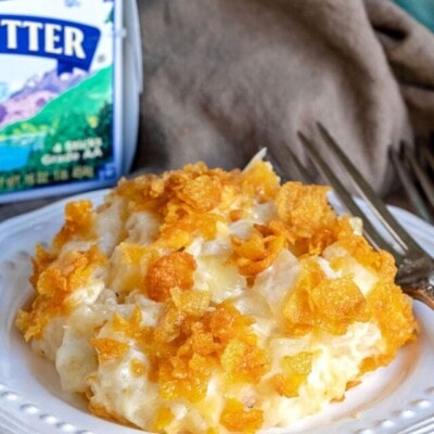 cheesy potatoes on white plate with challenge butter box behind it