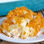 cheesy potatoes on a white plate with casserole dish in background