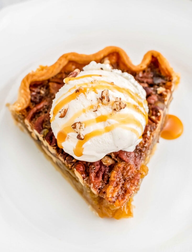 maple pecan pie recipe on white plate topped with vanilla ice cream and caramel drizzle