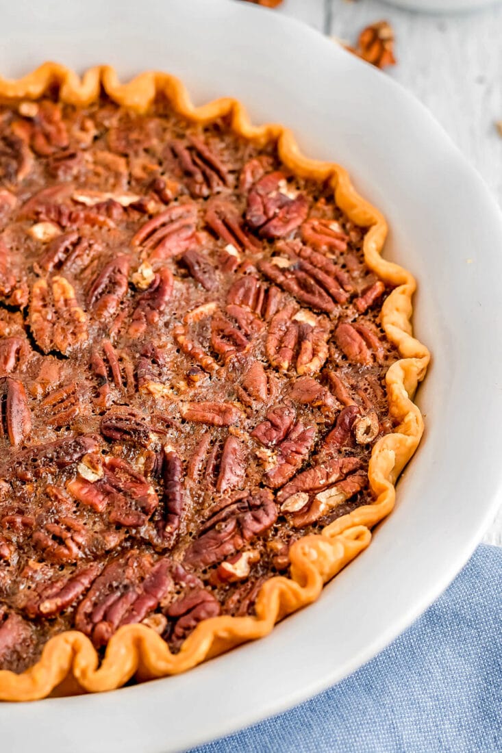 whole pecan pie in pie plate with light blue napkin beneath