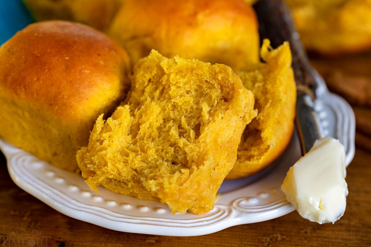 pumpkin dinner roll split in half on white plate