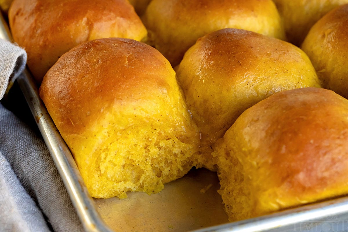 pumpkin dinner rolls baked in sheet pan with one removed