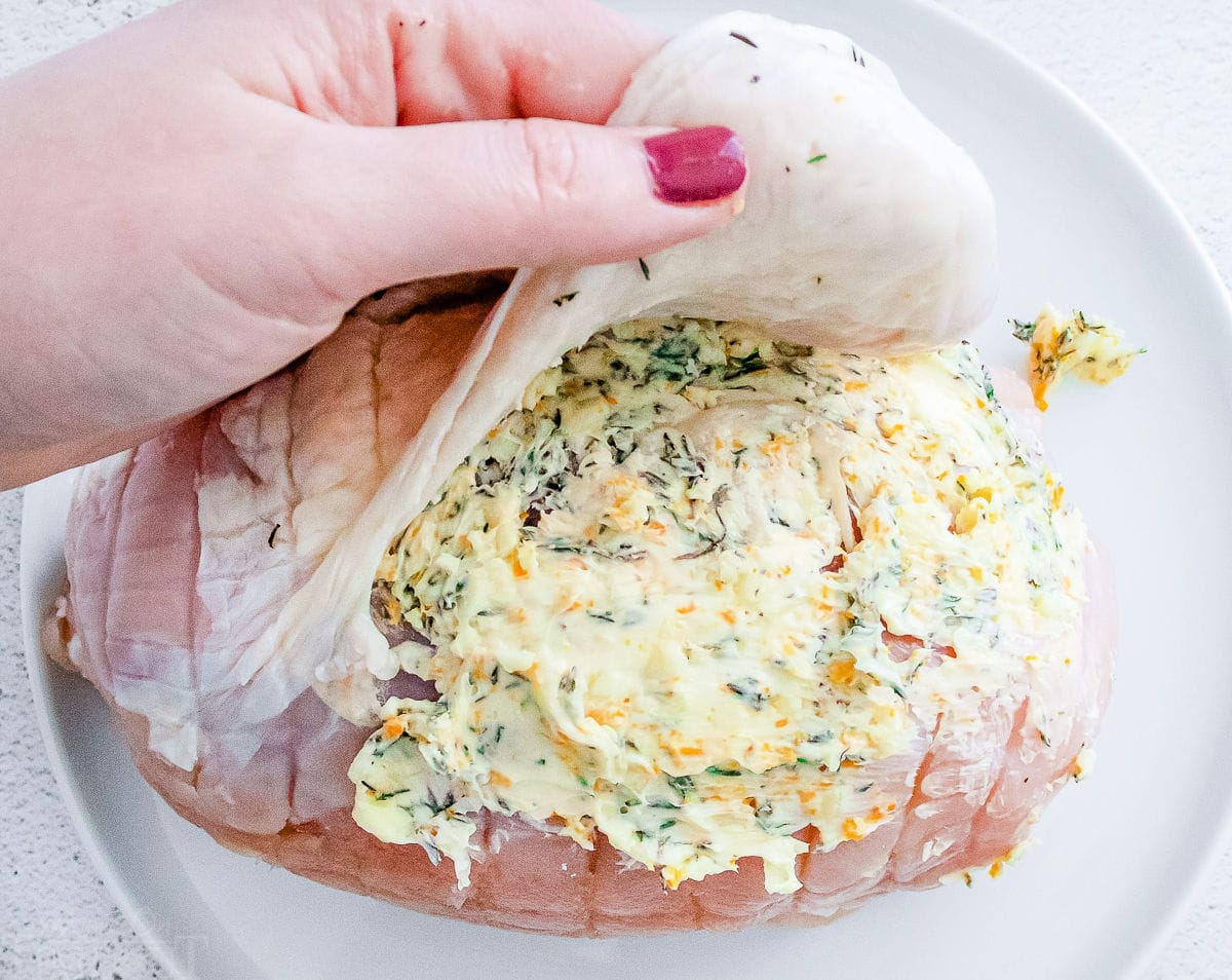 roast turkey breast with compound butter being stuffed under the skin