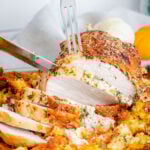 roast turkey breast being sliced on sheet pan with sides around it