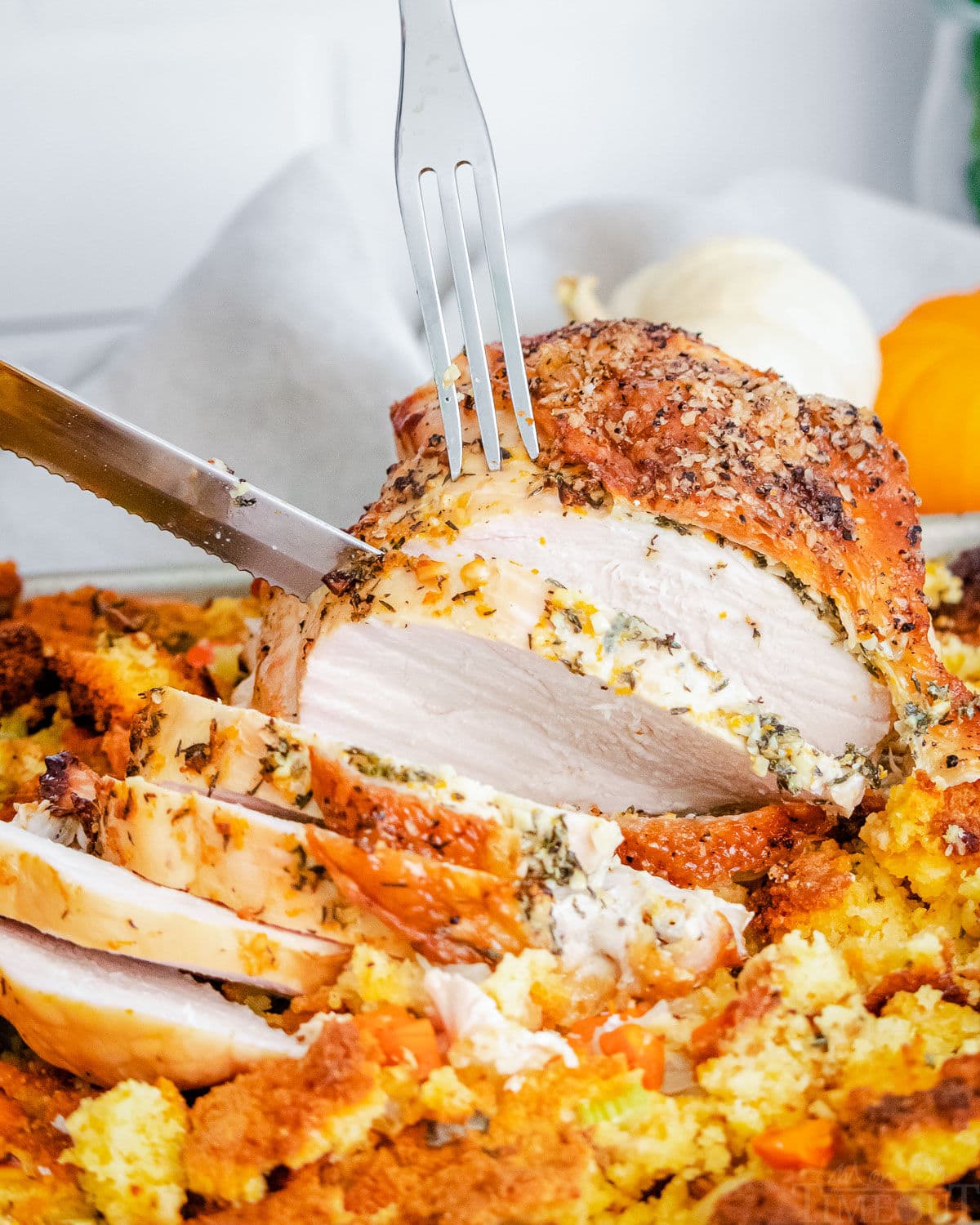 roast turkey breast being sliced on sheet pan with sides around it