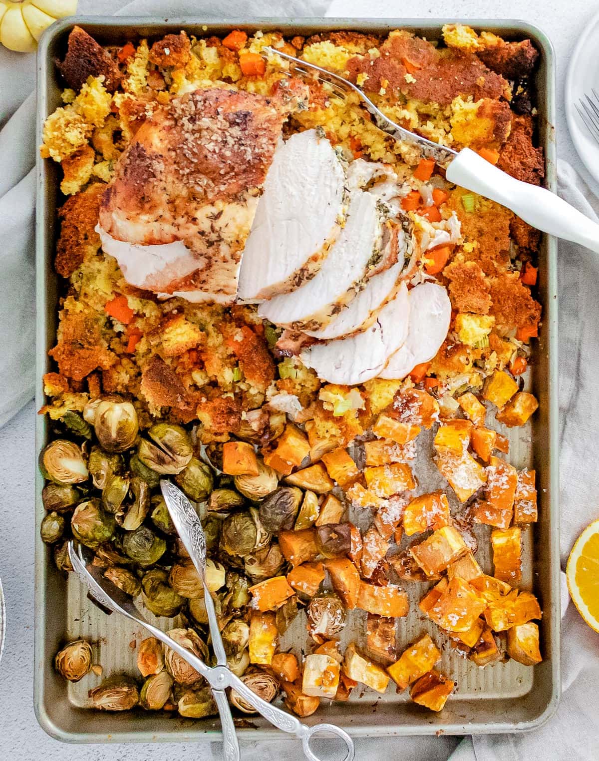 top down look at sheet pan with the turkey and sides and serving spoons
