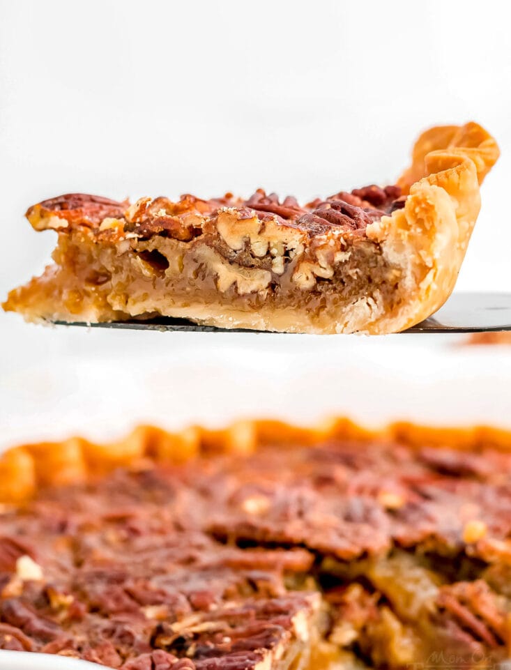 slice of pecan pie on pie server with pie beneath