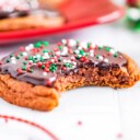 cookie with bite out of it sitting on white surface with more chocolate cookies in background