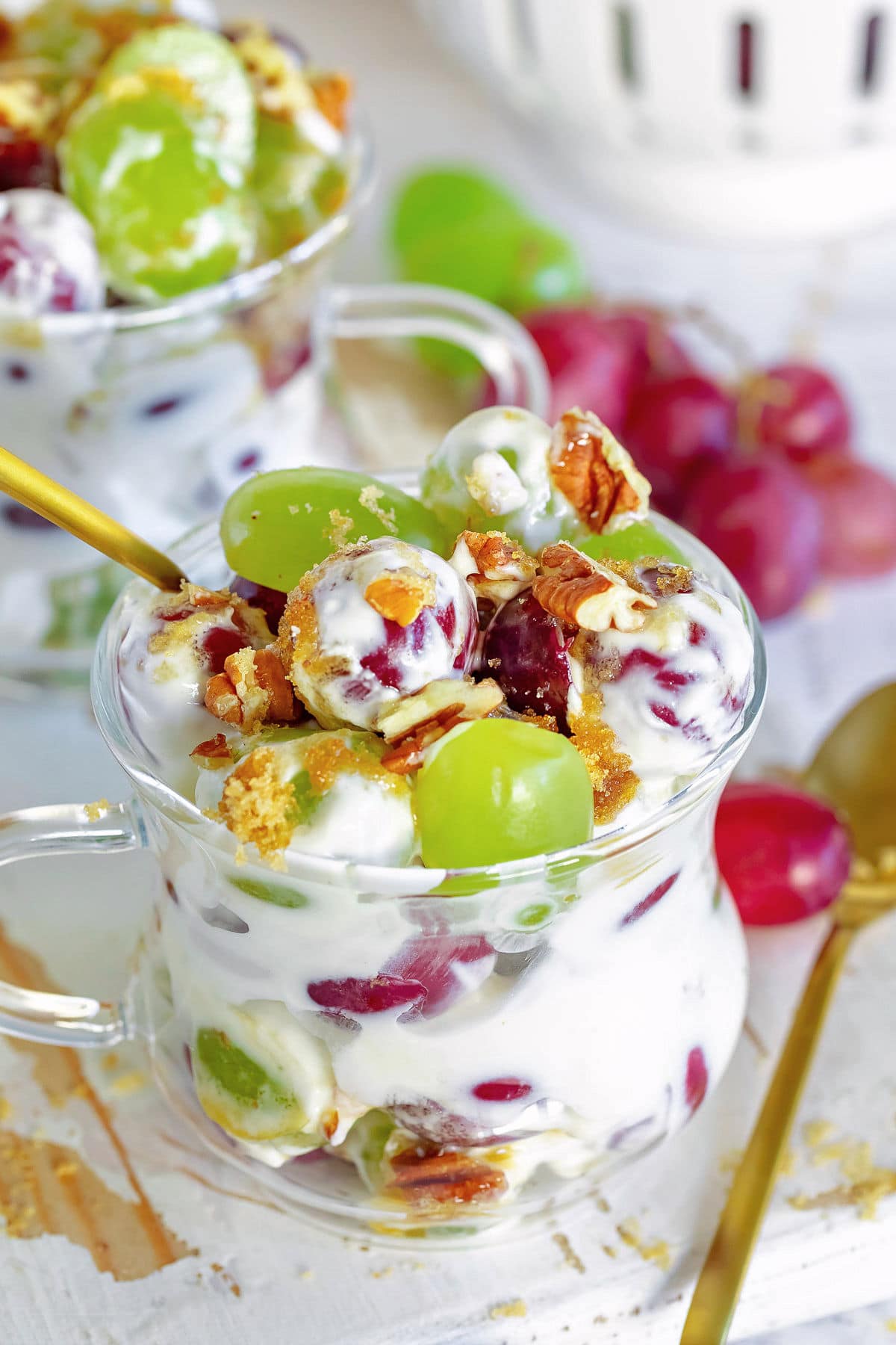 grape salad with cream cheese dressing in small cup with gold spoon