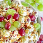 top down view of grape salad in clear bowl topped with cut grapes and pecans and brown sugar