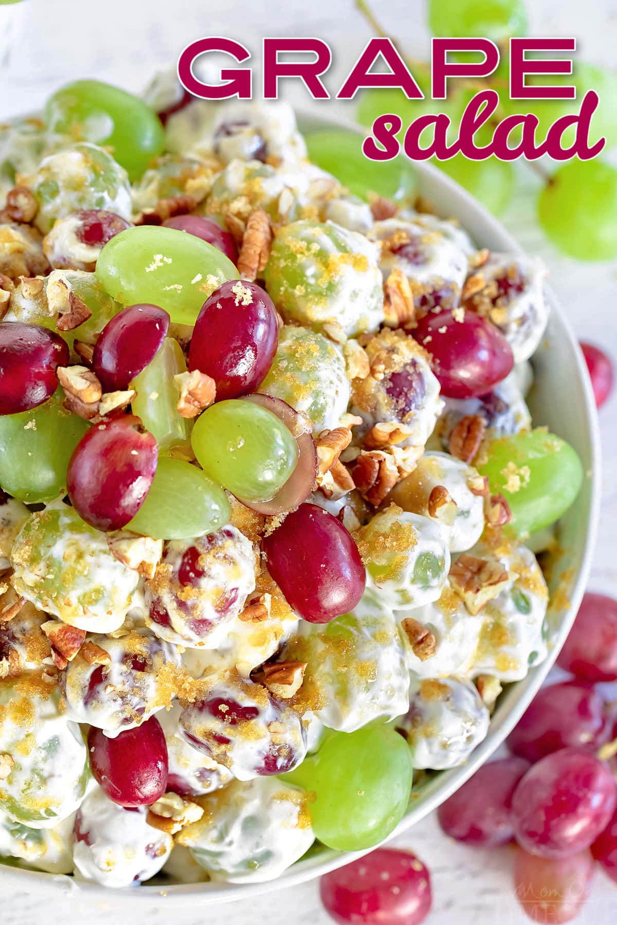 top down view of grape salad in clear bowl topped with cut grapes and pecans and brown sugar with a title overlay at top of image