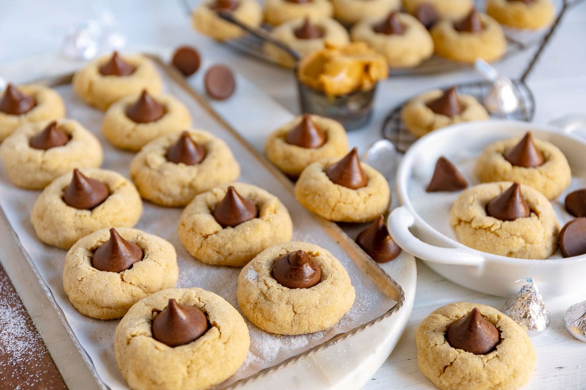 cookies on metal tray lined with parchment and more cookies in background and scattered about