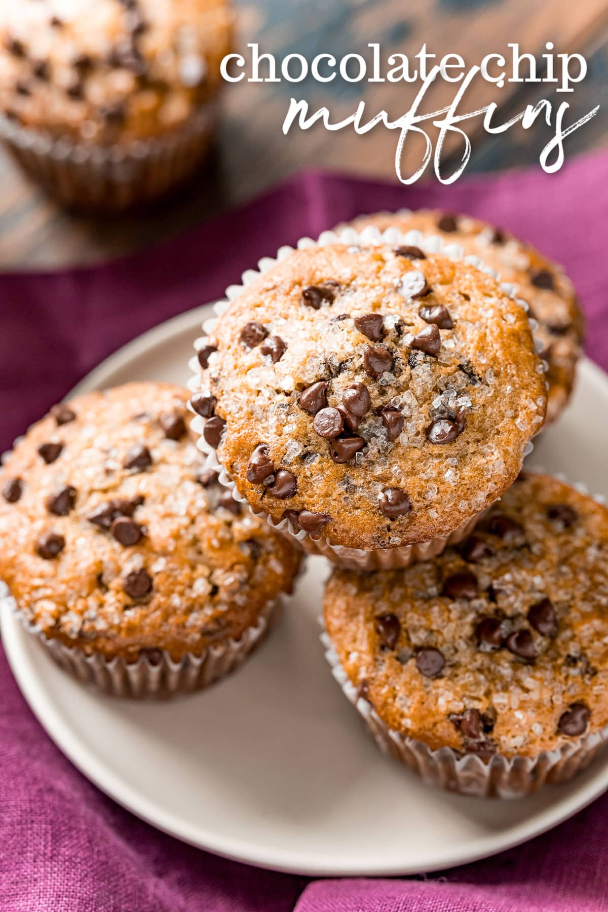 four chocolate chip muffins on a white plate with a burgundy napkin beneath the plate and title overlay at top of image