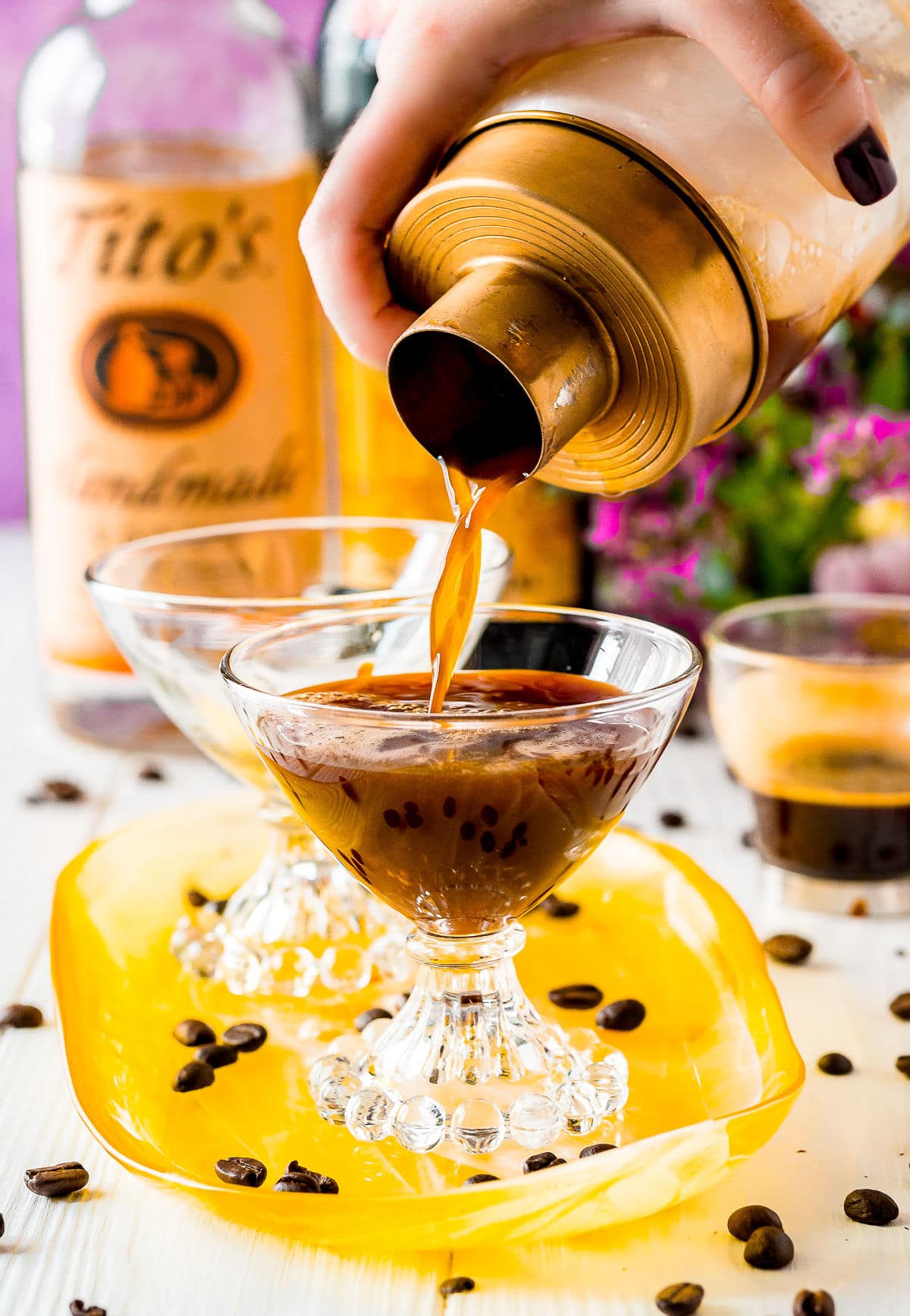 espresso martini being poured into glass from gold rimmed shaker