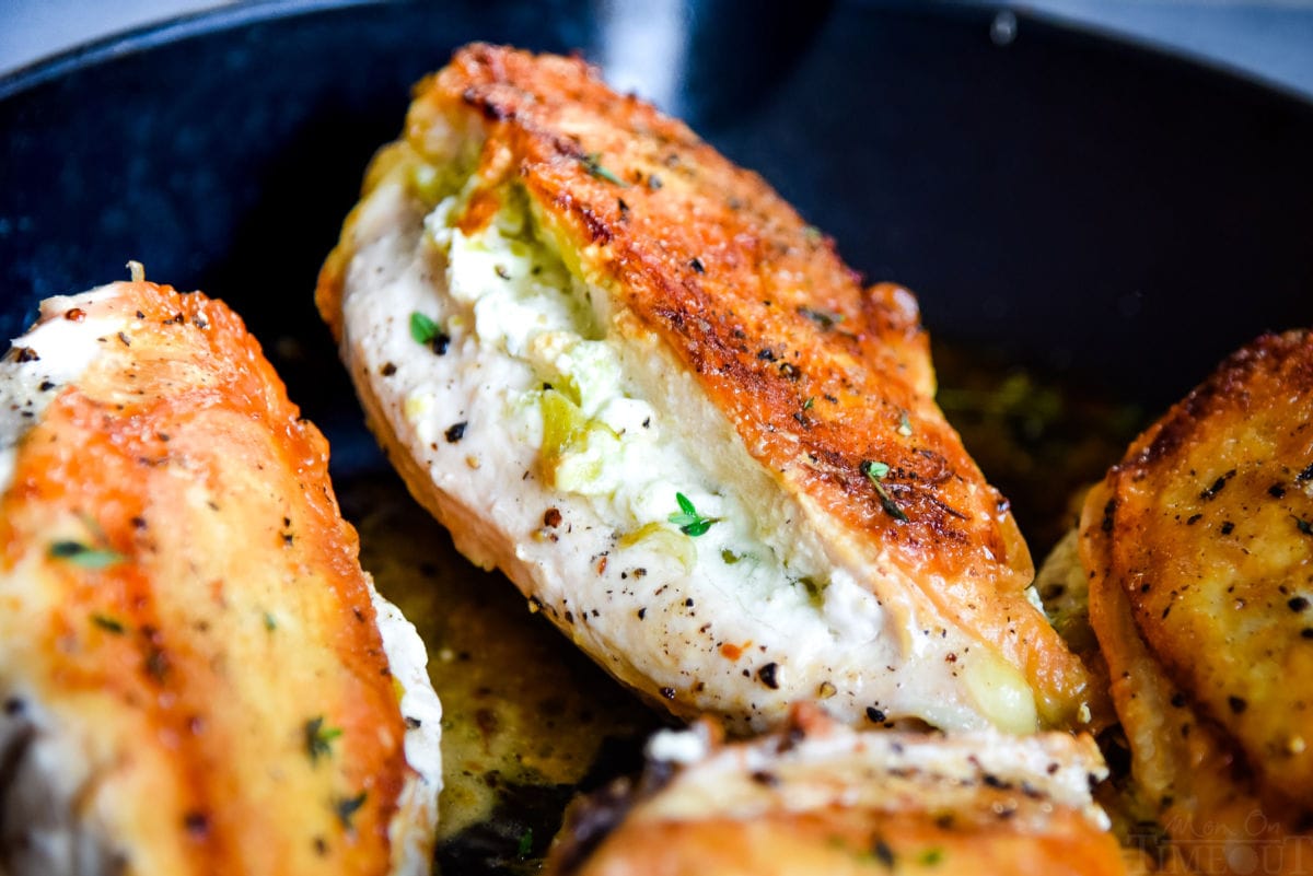 chicken breasts in skillet stuffed with pepperoncini and goat cheese with golden brown skin