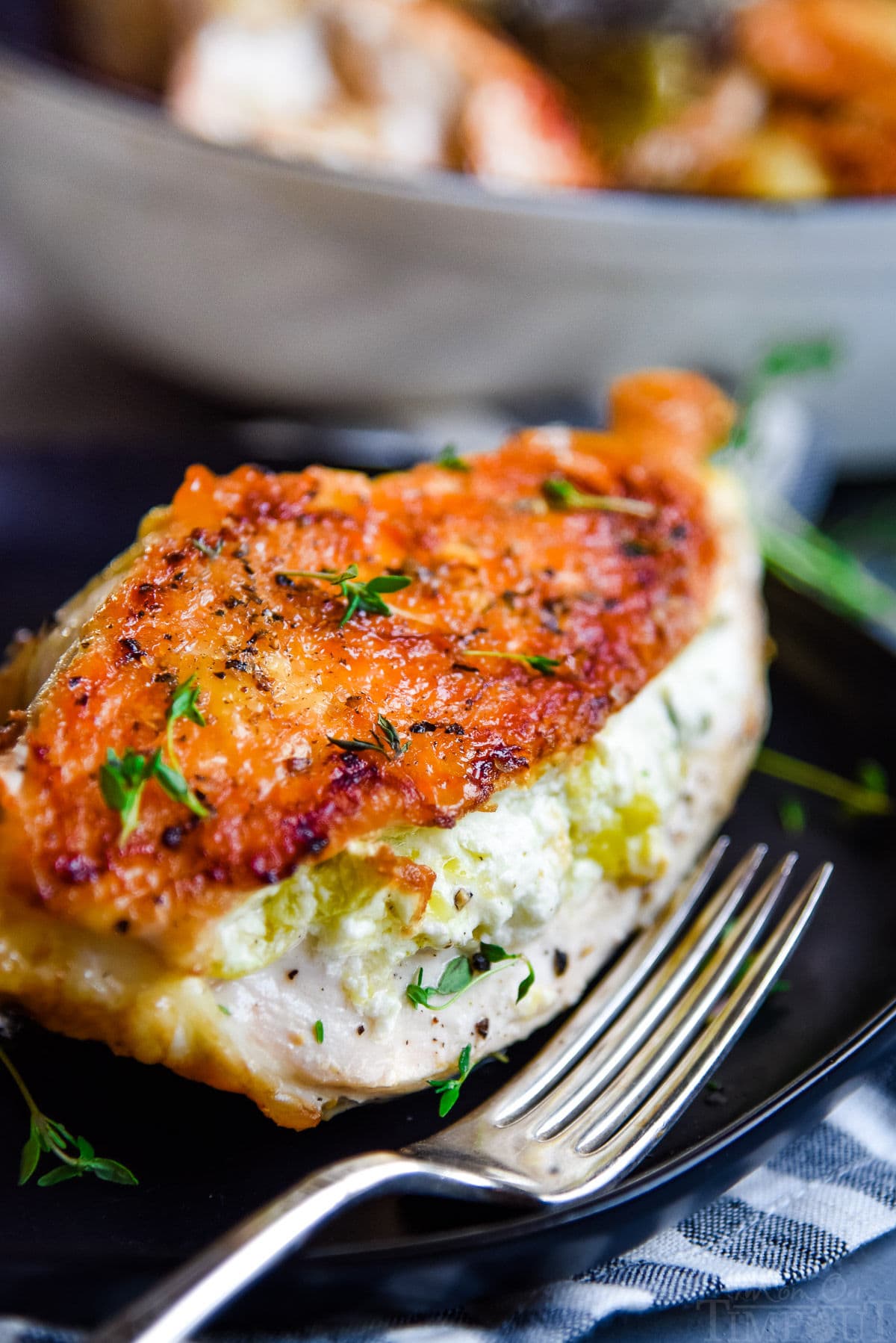 stuffed chicken with crispy skin on black plate with fork 