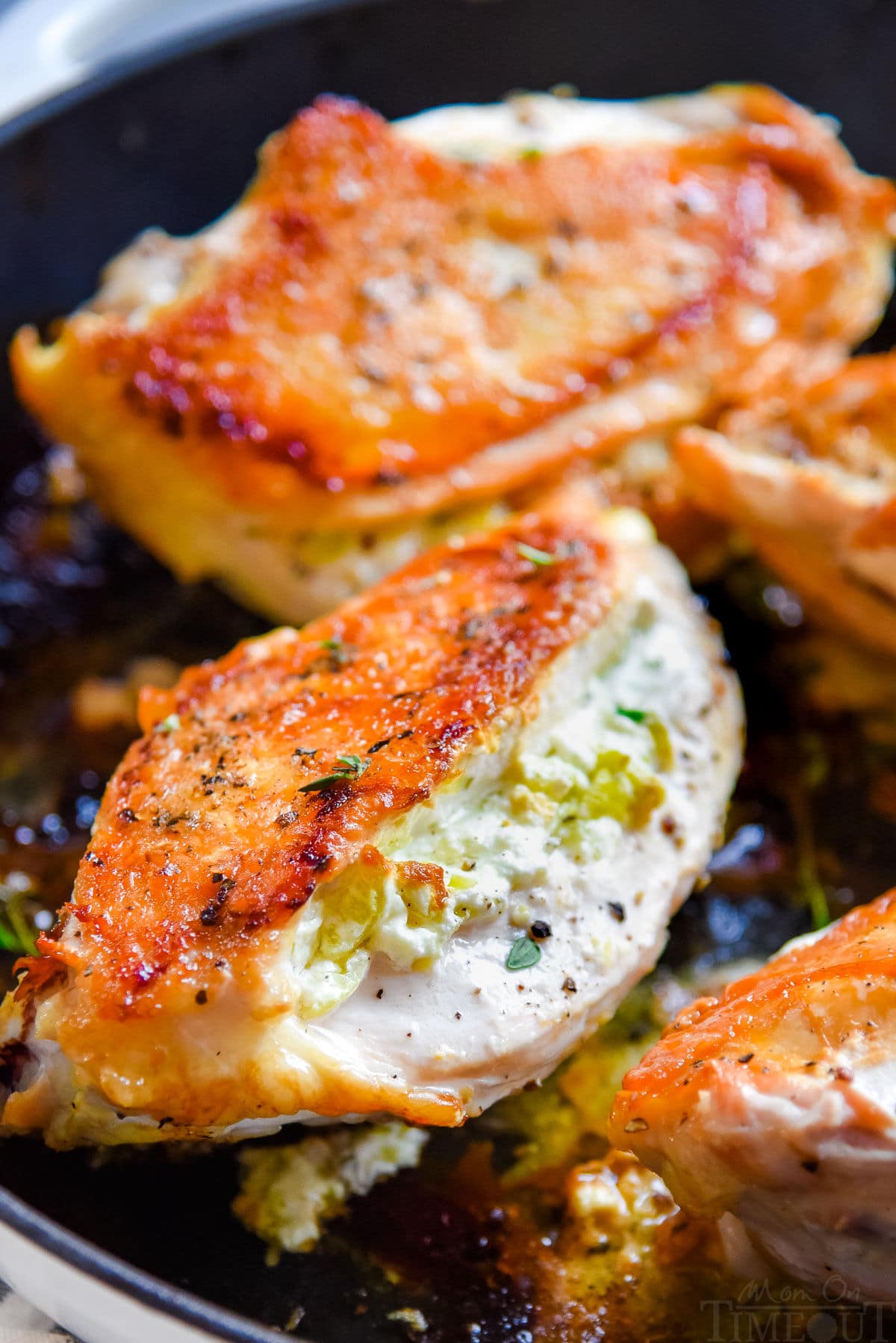 four chicken breasts in cast iron skillet stuffed with goat cheese filling