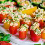 close up of stuffed hummus veggies topped with fresh herbs