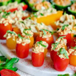 close up of stuffed hummus veggies topped with fresh herbs