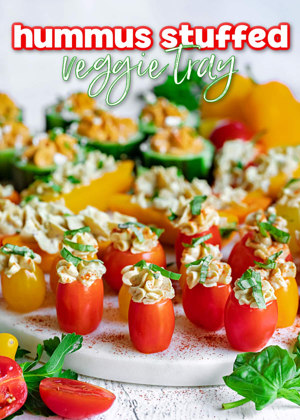 hummus stuffed veggies on white marble tray topped with herbs and title overlay at top 