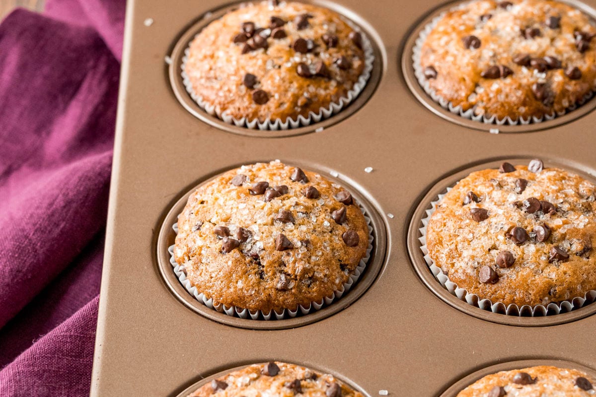 baked muffins in gold muffin tin with burgundy napkin to the side