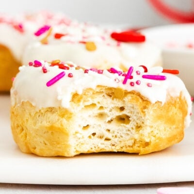 air fryer biscuit donut with vanilla glaze and valentines day sprinkles with bite taken