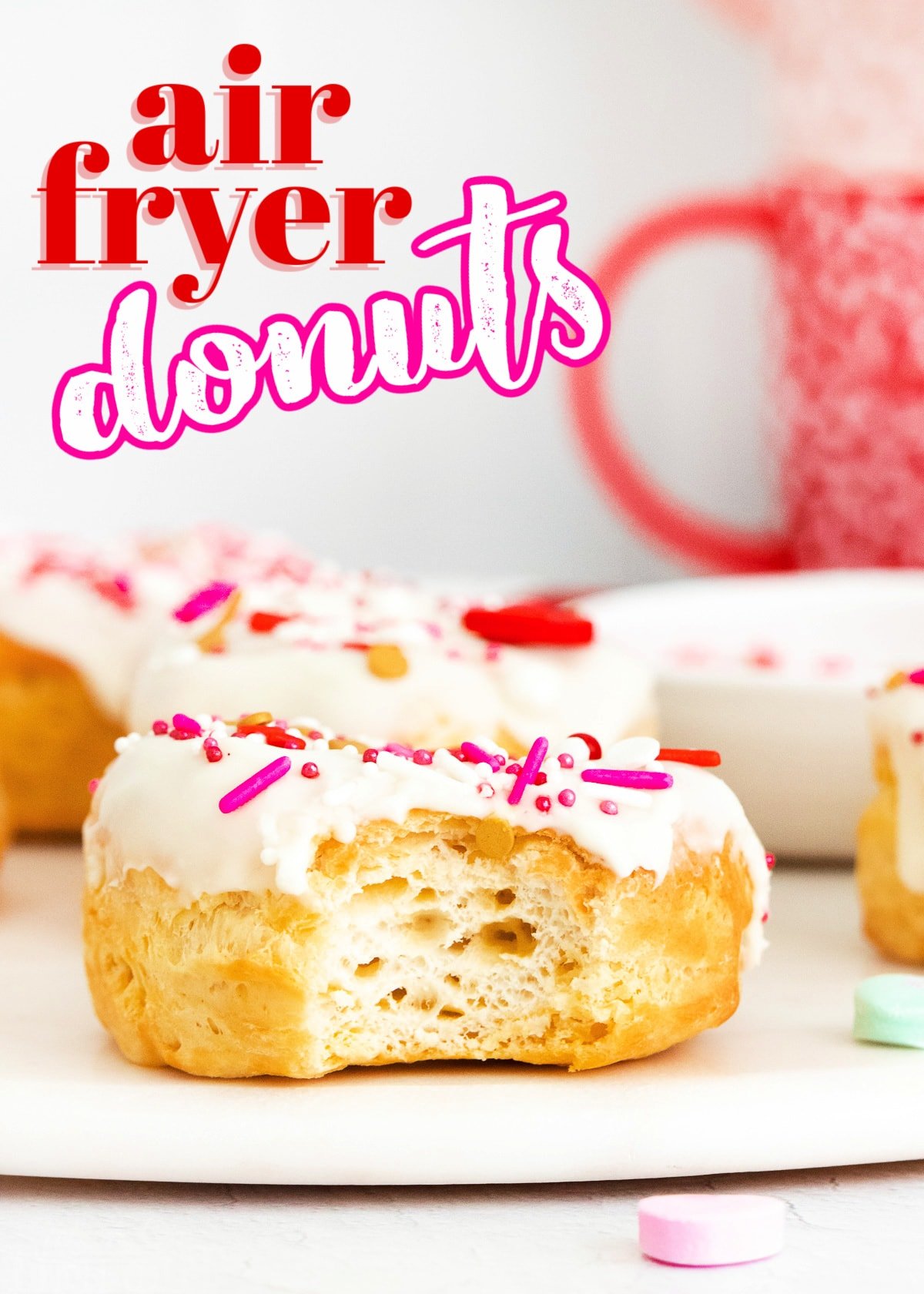 air fryer donut with vanilla glaze and valentines day sprinkles with bite taken and title overlay at top of image