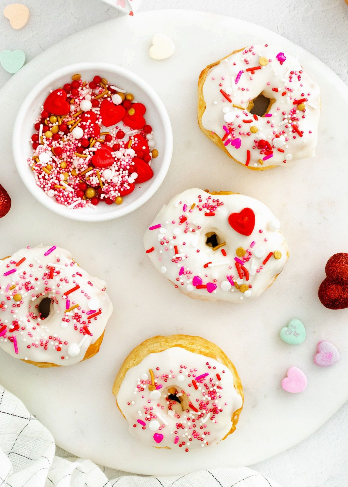 4 donuts decorated for Valentine's Day on marble round surface