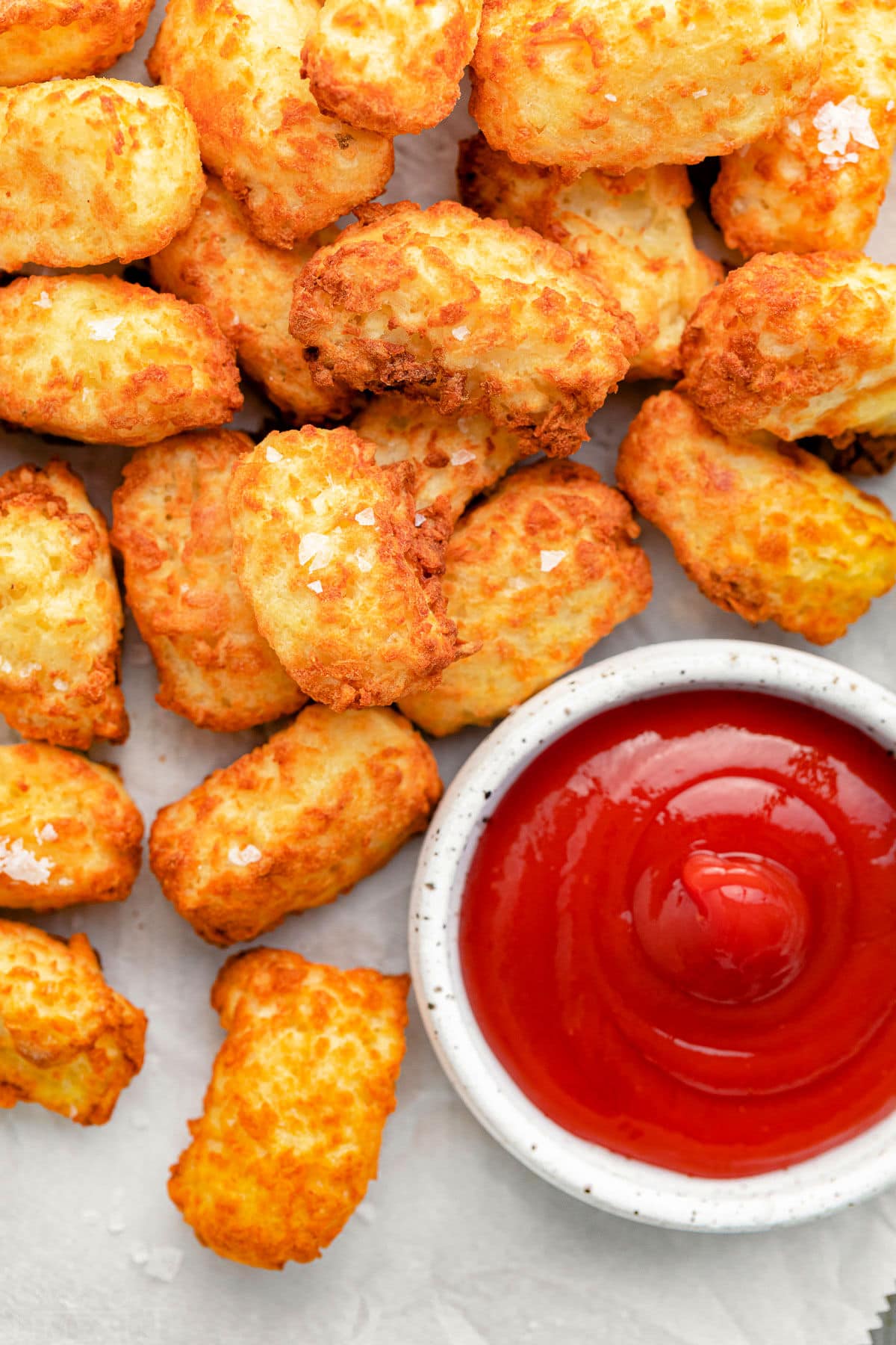 close up of golden crispy tater tots with ketchup.