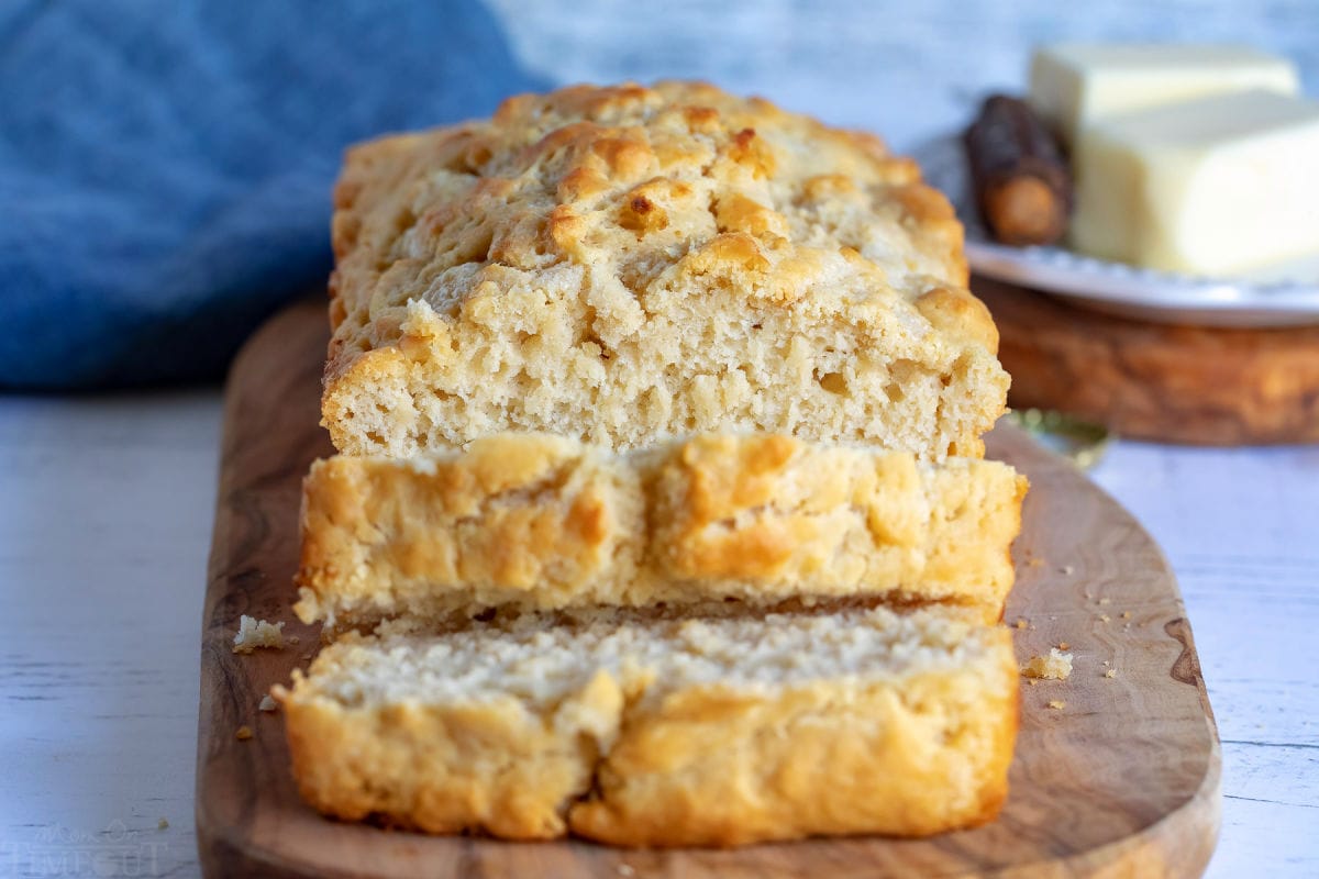 beer bread sliced with two slices sitting on cutting board.