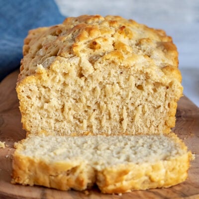 beer bread sitting on board with one slice.