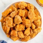 chicken nuggets piled high on a white plate.