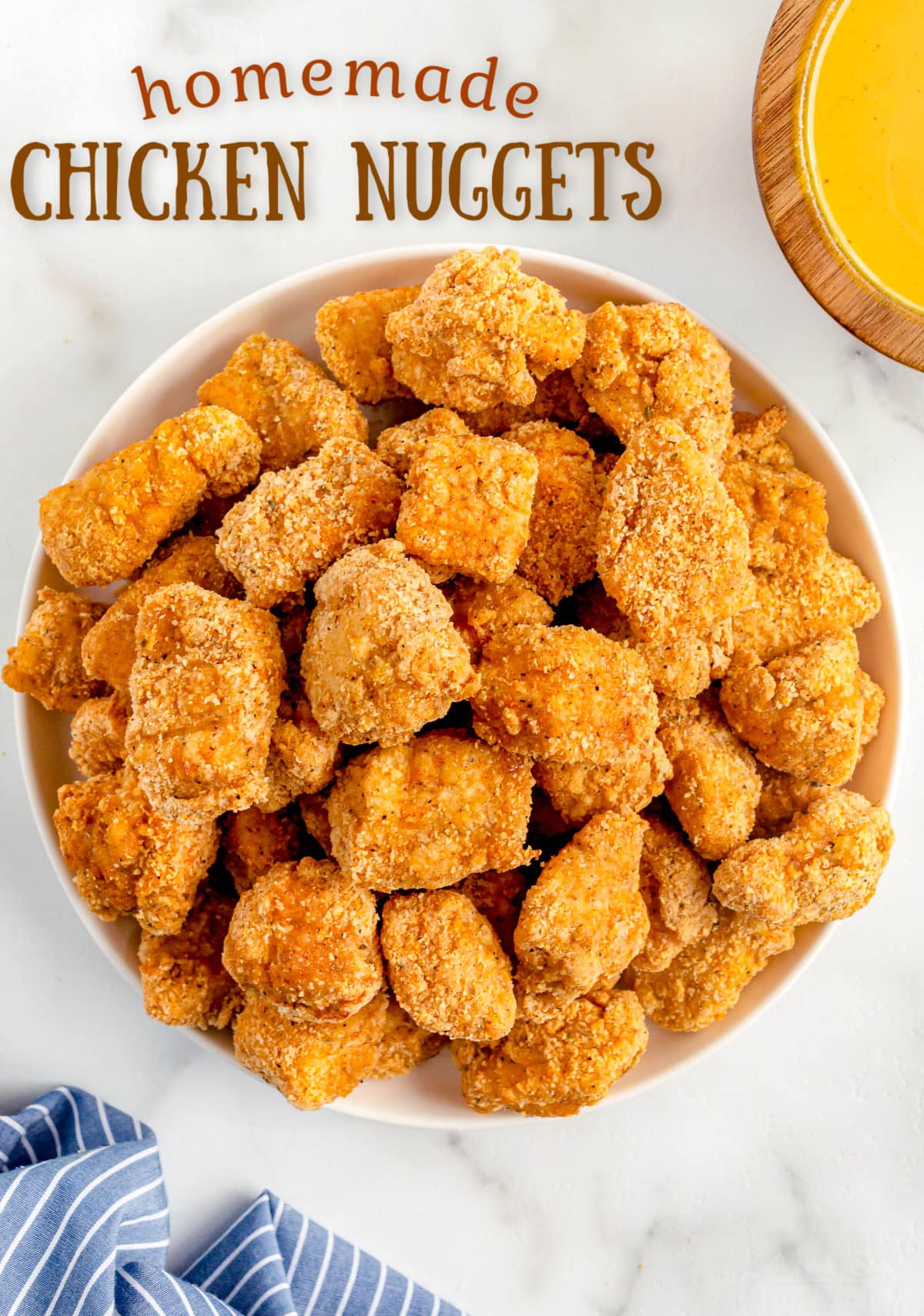 chicken nuggets piled high on white plate with title overlay at top.