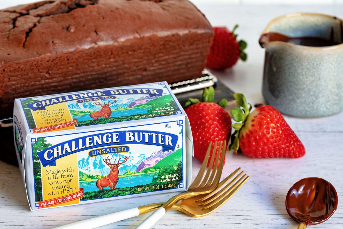 chocolate pound cake with challenge butter box sitting in front with a couple forks and strawberries