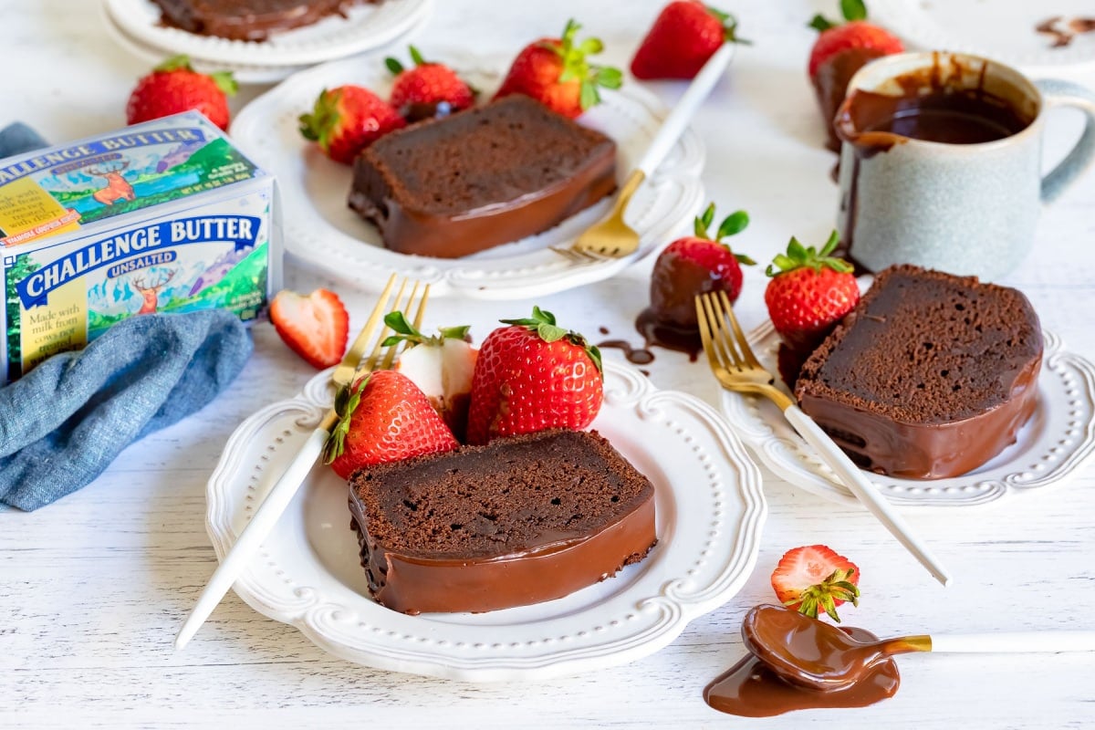 chocolate pound cake sliced and served on plates with chocolate glaze and strawberries