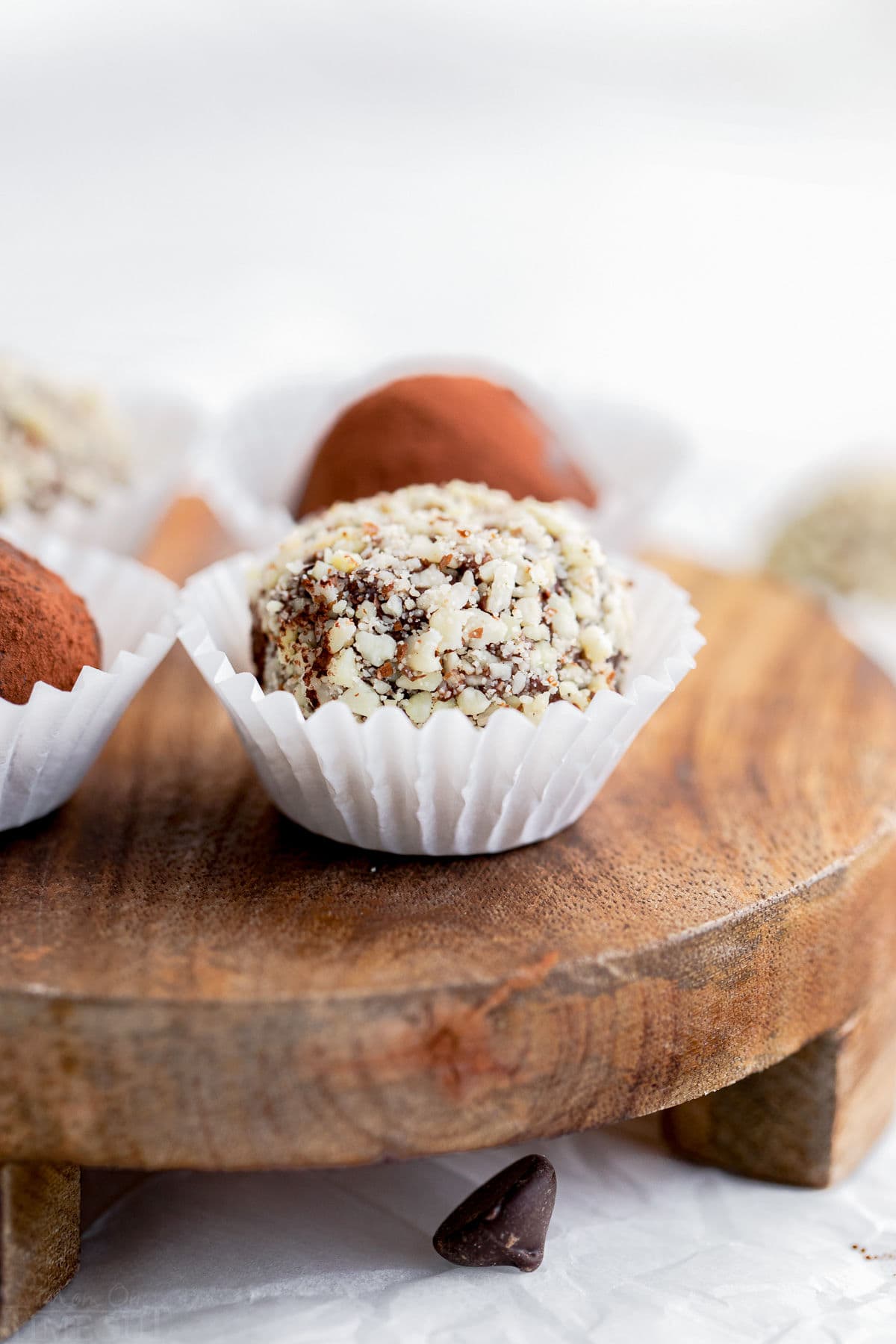 chocolate truffle coated in almonds in white paper cup on wood board