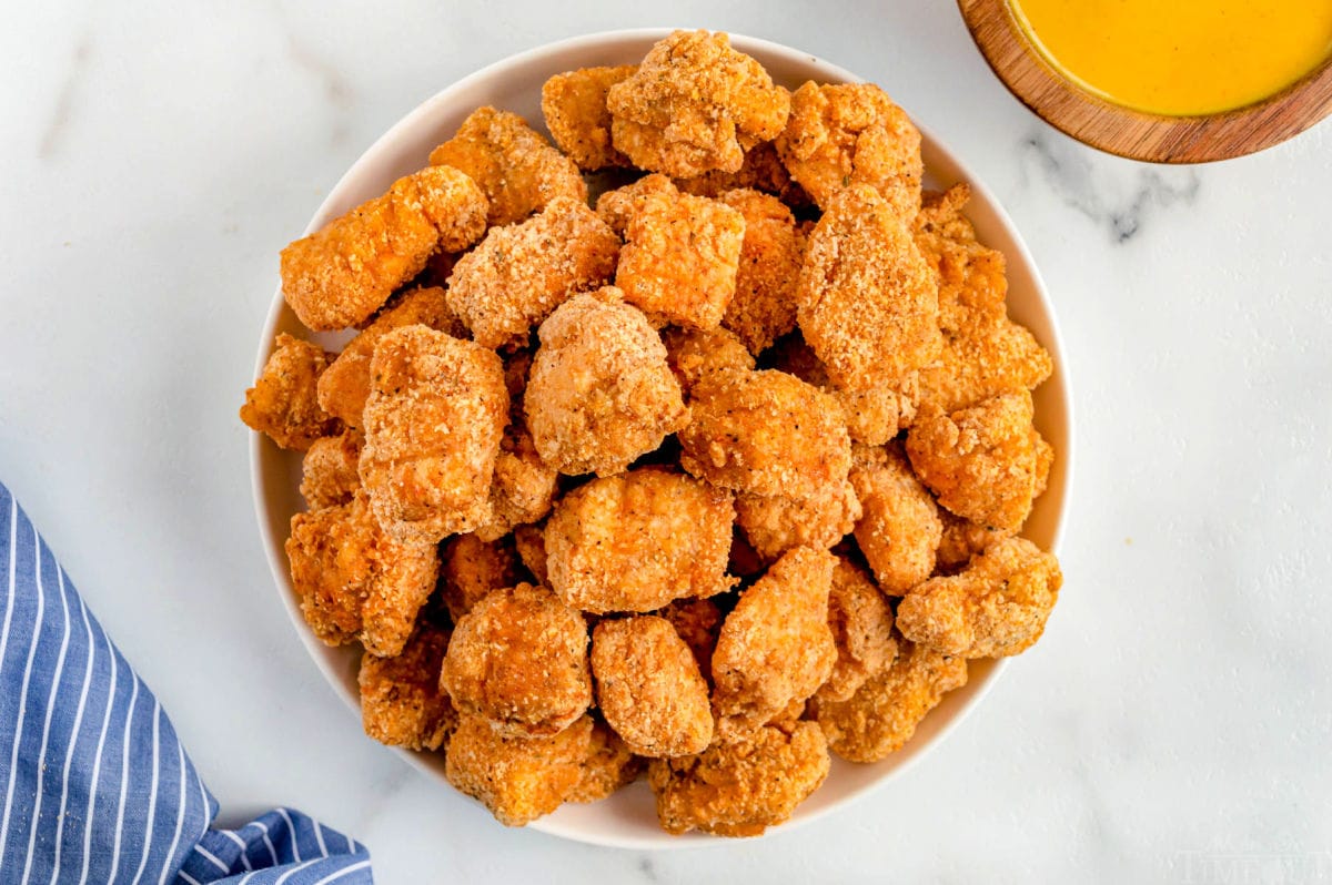 chicken nuggets piled high on a white plate.