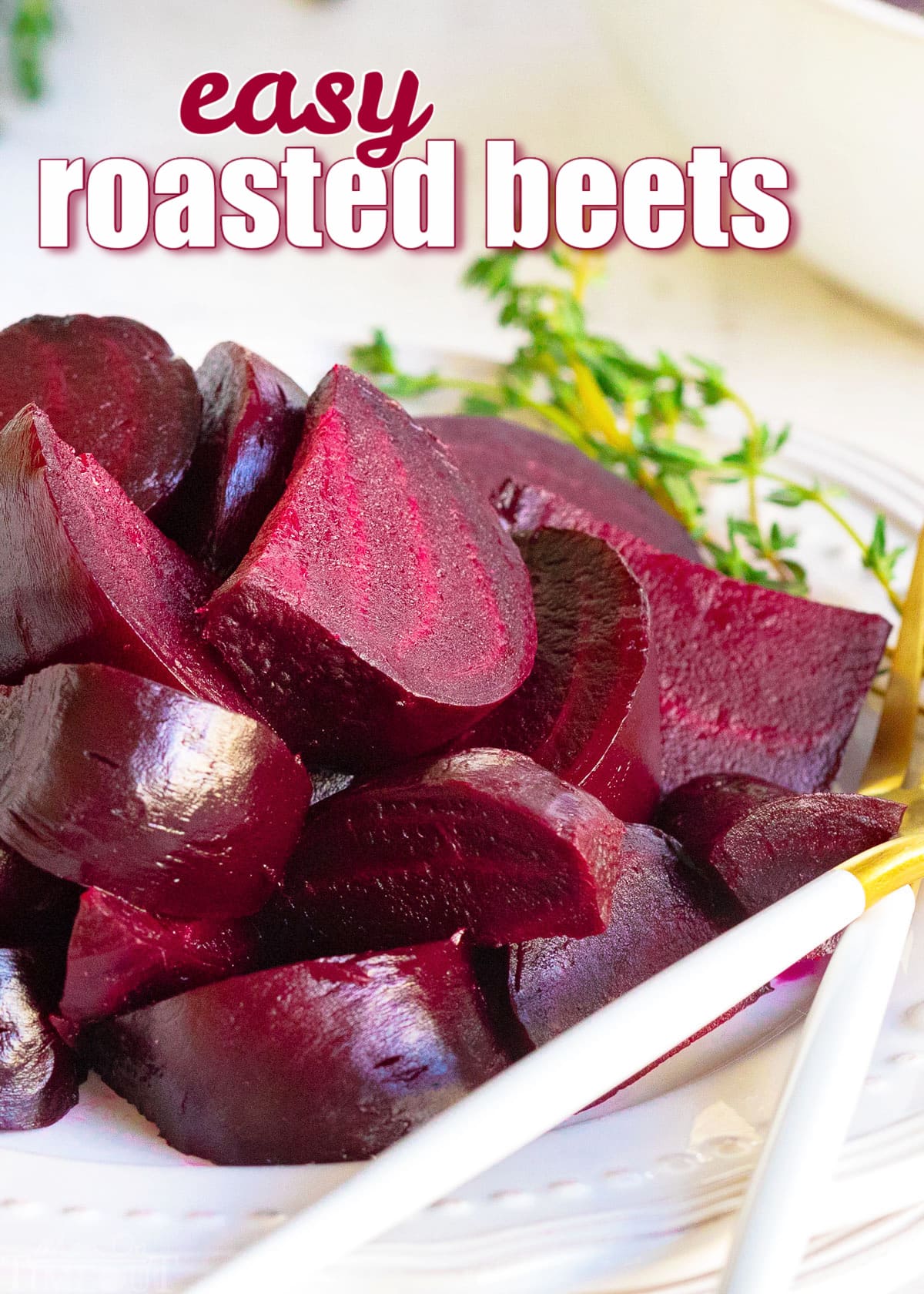 roasted beets cut into wedges on white plate with thyme sprig on plate.