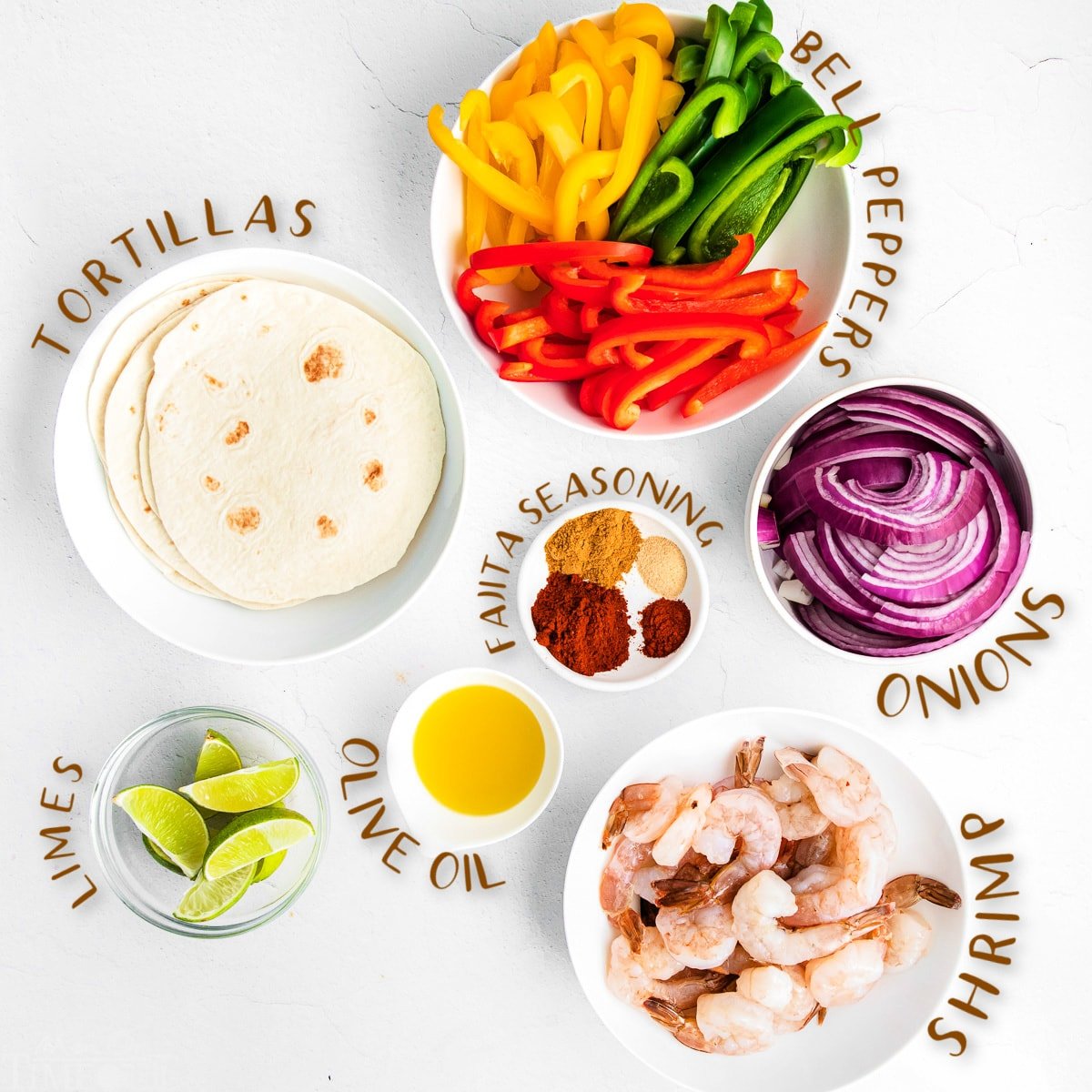 fajita ingredients all measured out in small bowls on white surface.