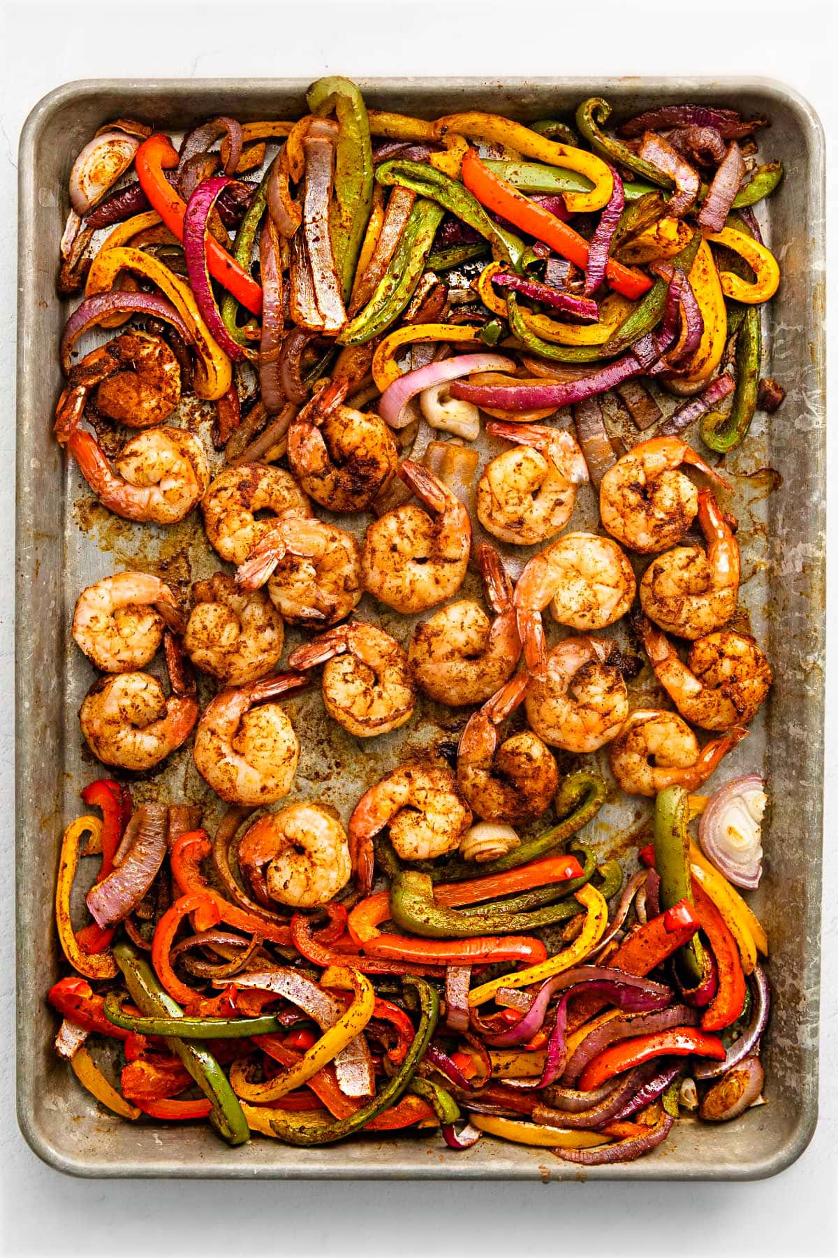 shrimp fajitas on a sheet pan with shrimp in the center and veggies on the sides.