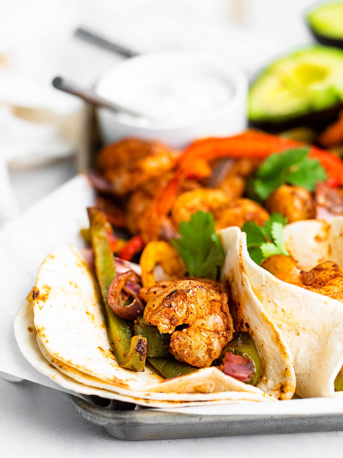 a couple of fajitas on a sheet pan topped with fresh cilantro.