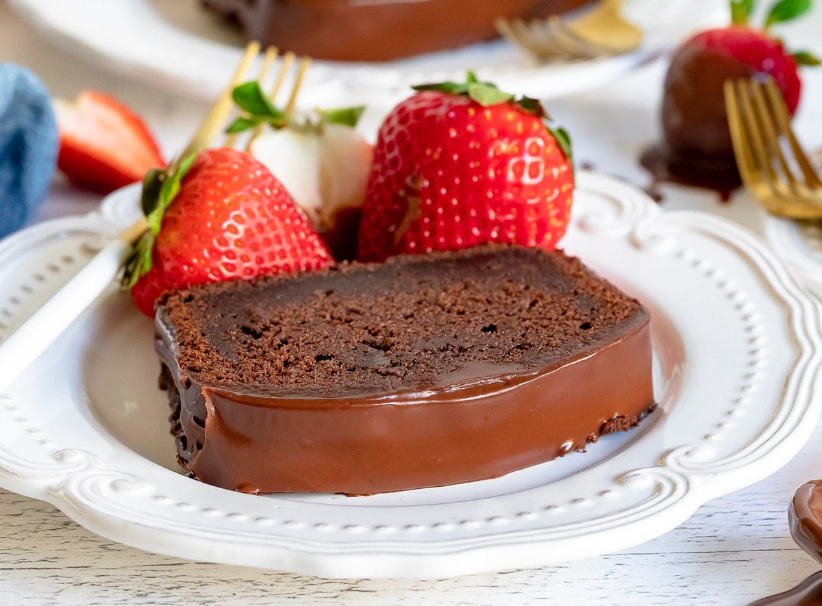 slice of chocolate pound cake on white plate with strawberries