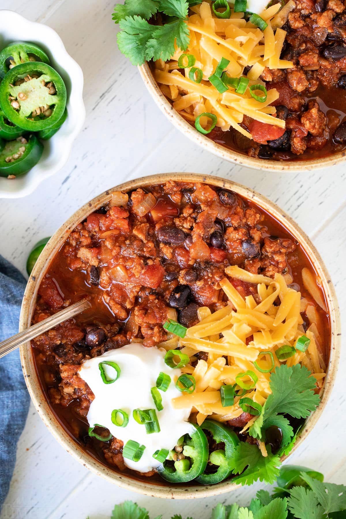 2 bowls of turkey chili with lots of toppings.