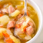 spoonful of soup held up over white bowl.