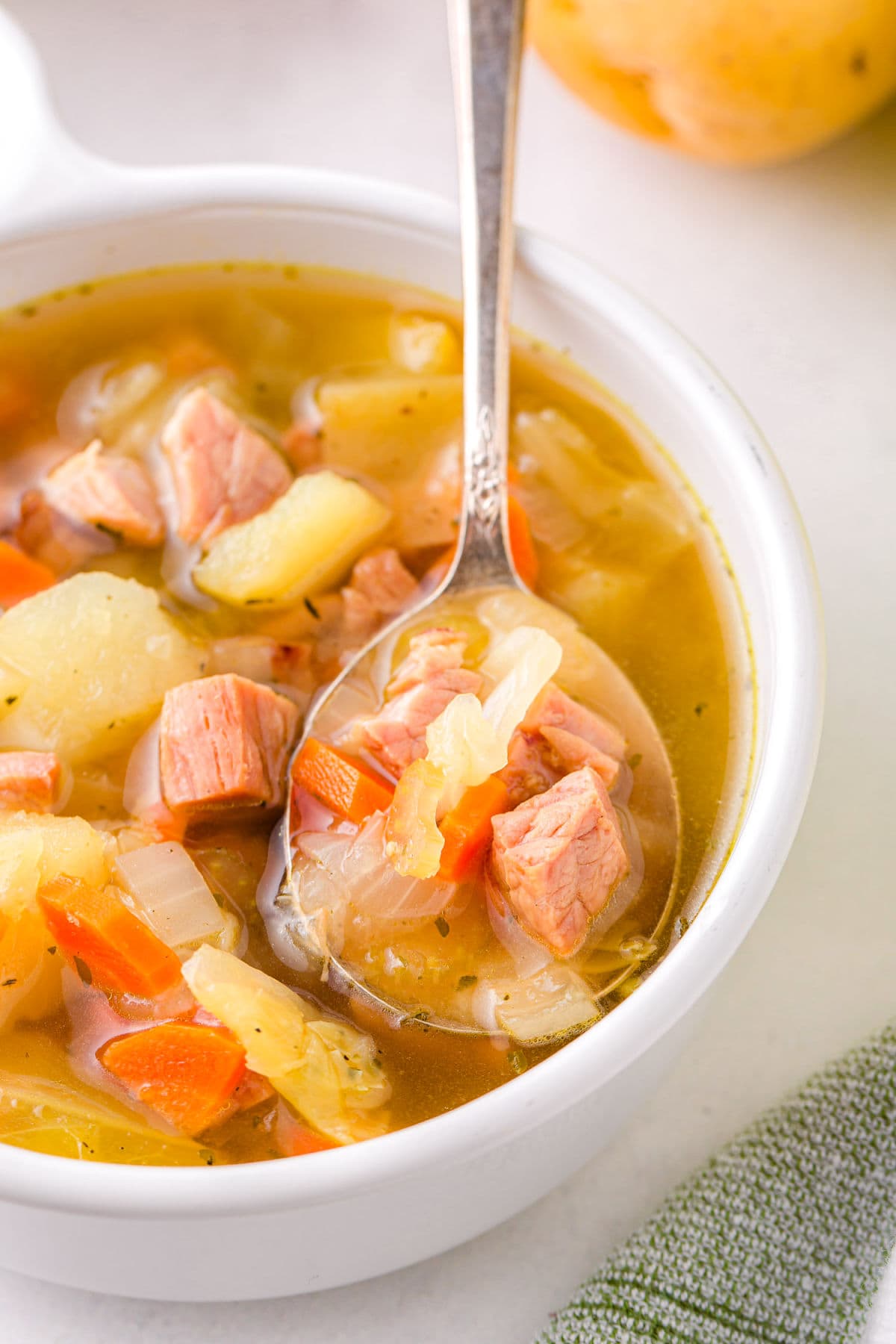 spoonful of soup held up over white bowl.