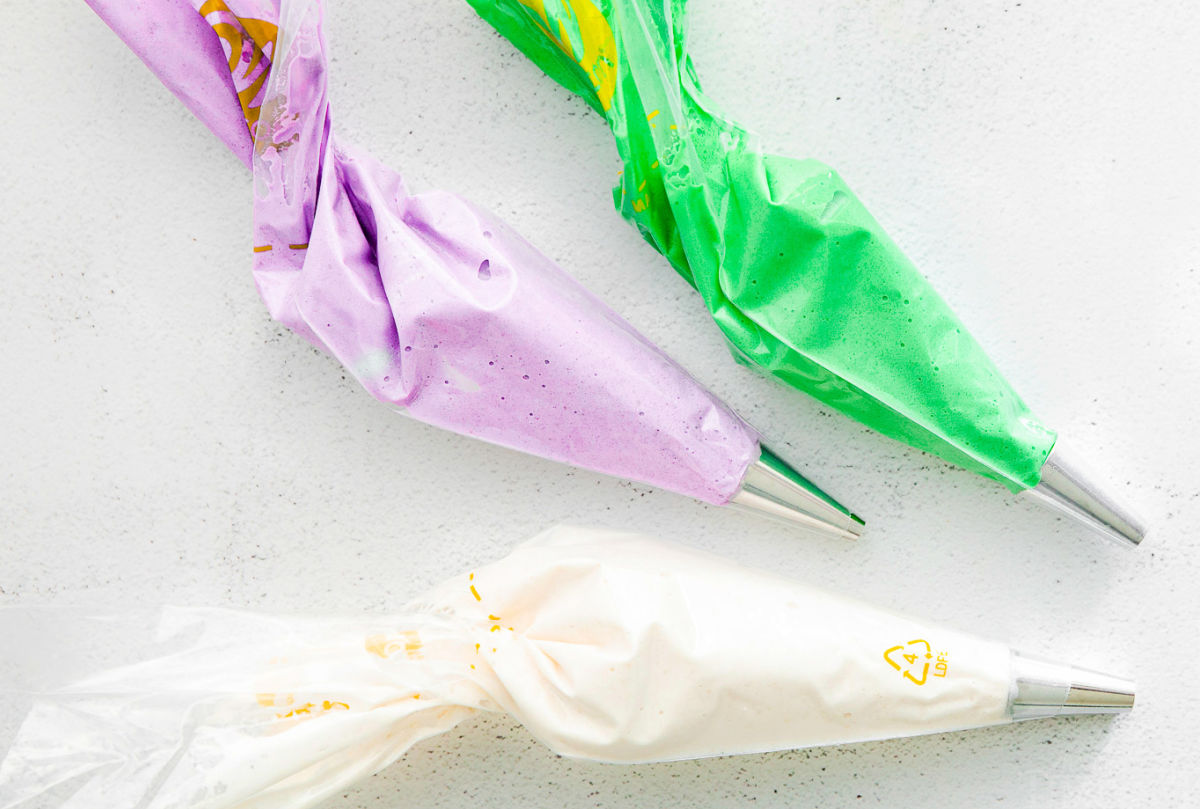 3 piping bags filled with colored macaron batter.