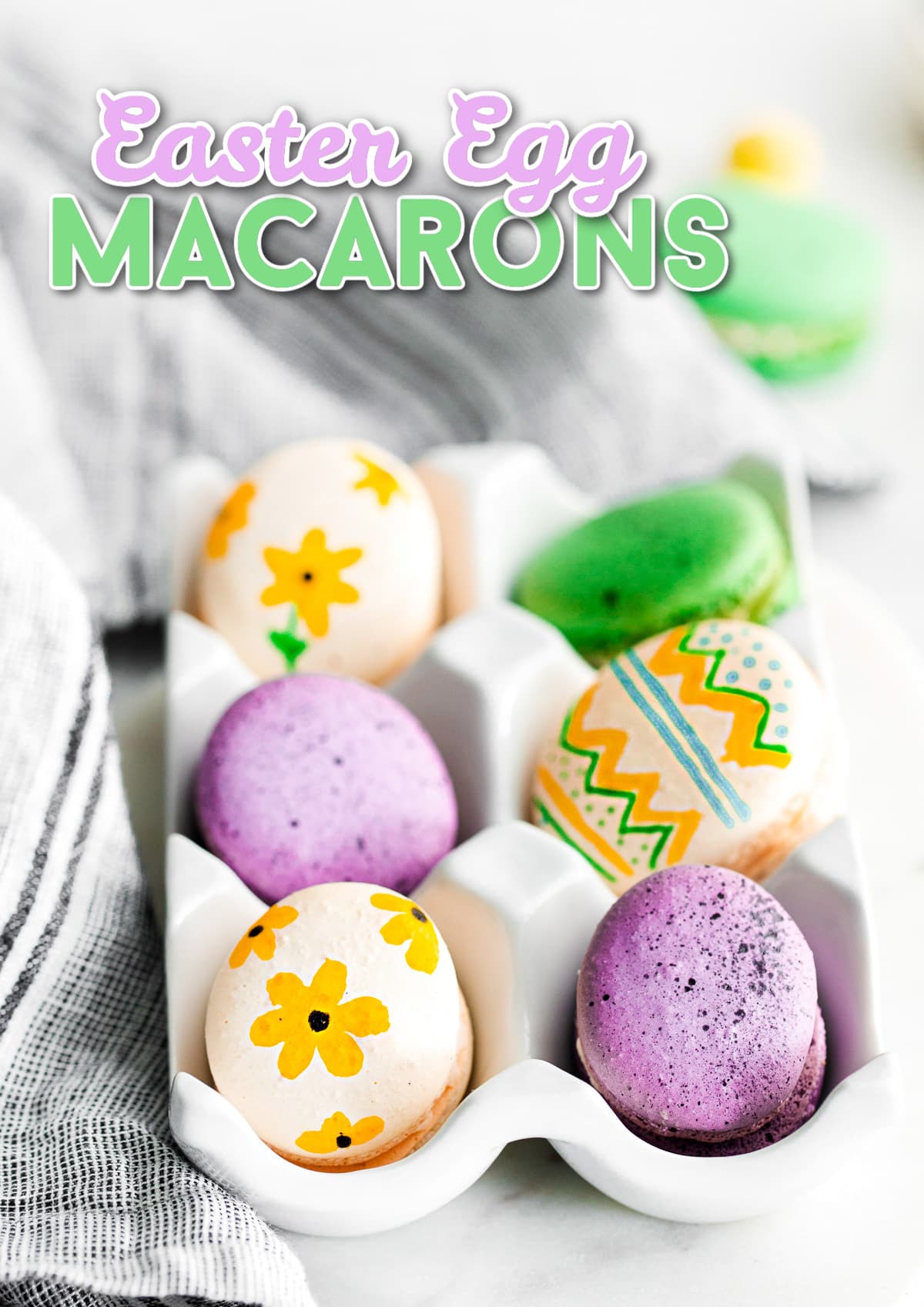 french macarons decorated as easter eggs sitting in white egg crate with title overlay at top of image.