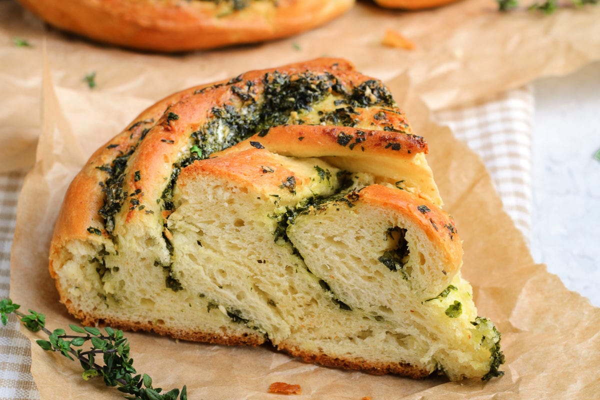 piece of garlic herb bread on brown parchment paper.