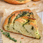 piece of garlic herb bread on brown parchment paper.