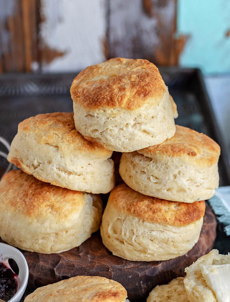 golden brown biscuits stacked high on wood board.